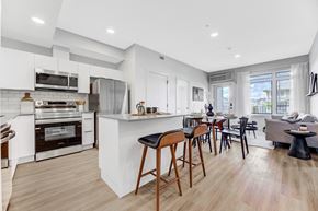 Edmonton apartment for rent - a living area with a kitchen and a dining area with bar stools