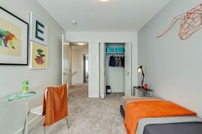 Saskatoon apartment for rent - A bedroom with a bed, a chair, and a painting on the wall.