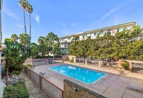 San Leandro apartment for rent - A pool surrounded by a fence and trees.
