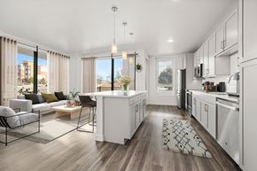Denver apartment for rent - A modern kitchen with white cabinets and a wooden floor.