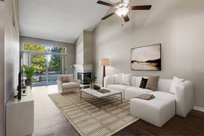 Sacramento apartment for rent - A living room with a white couch, a rug, and a ceiling fan.