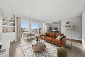 Alameda apartment for rent - A living room with a brown sofa, a coffee table, and a large window with a view of the city.