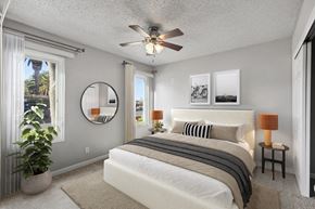 Livermore apartment for rent - A bedroom with a large bed, a ceiling fan, and a mirror on the wall.