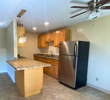 San Leandro apartment for rent - A kitchen with a black refrigerator and wooden cabinets.