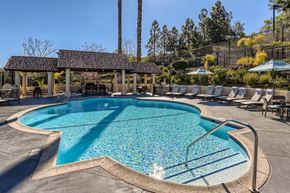 Simi Valley apartment for rent - A large outdoor swimming pool surrounded by sun loungers and umbrellas.