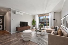 Walnut Creek apartment for rent - A living room with a brown sofa, a white ottoman, and a wooden floor.