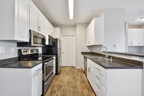 San Jose apartment for rent - A kitchen with white cabinets and black countertops.