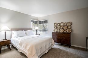 Sacramento apartment for rent - A bedroom with a bed, nightstand, and a dresser with plates on it.