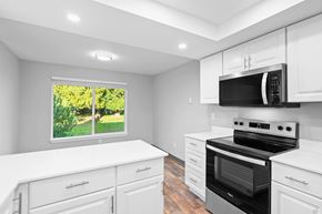 Vancouver apartment for rent - A kitchen with white cabinets and a black stove top oven.