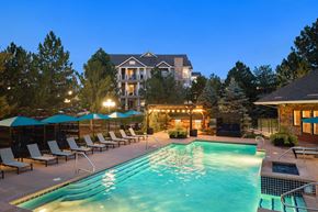 Parker apartment for rent - A large swimming pool surrounded by lounge chairs and umbrellas in front of a large house.