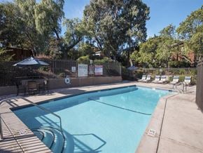 Benicia apartment for rent - A pool surrounded by trees and a fence with a sign on it.