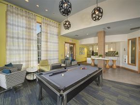 Riverside apartment for rent - A pool table is in the middle of a room with a yellow wall and a window with yellow curtains.
