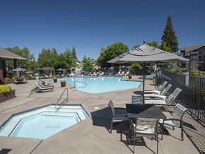 Roseville apartment for rent - A large outdoor swimming pool surrounded by lounge chairs and umbrellas.