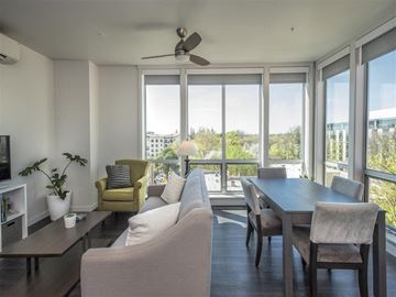 Sacramento apartment for rent - A living room with a yellow chair and a ceiling fan.