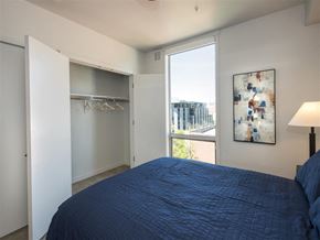 Sacramento apartment for rent - A bedroom with a blue bedspread and a large window.
