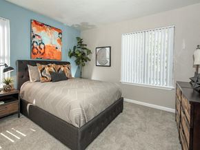 Vacaville apartment for rent - A bedroom with a large bed, a nightstand, and a painting on the wall.
