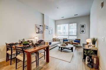 Denver apartment for rent - A well-lit living room with a dining table and a couch.