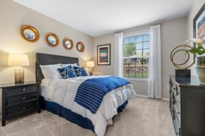 Lakewood apartment for rent - A bedroom with a large bed and a window with white curtains.