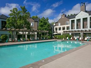 Beaverton apartment for rent - A large swimming pool in front of a building with a patio area.
