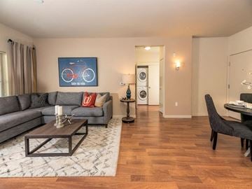 Tigard apartment for rent - A living room with a grey couch, a coffee table, and a painting of a red bicycle on the wall.