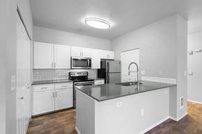 Beaverton apartment for rent - A kitchen with white cabinets and a black countertop.