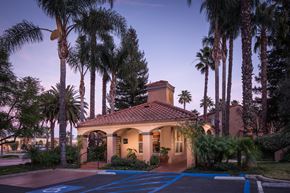 Simi Valley apartment for rent - A house with a red tile roof is surrounded by palm trees.
