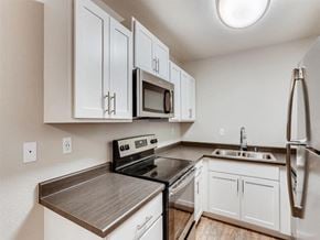 Renton apartment for rent - A kitchen with white cabinets and a black stove top oven.
