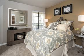 Rancho Cordova apartment for rent - A bedroom with a large bed and a mirror above a dresser.