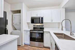 Livermore apartment for rent - A kitchen with white cabinets and a black fridge.