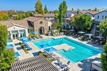 Roseville apartment for rent - A large swimming pool surrounded by lounge chairs and umbrellas.