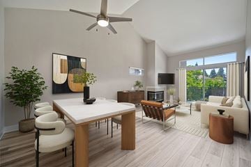 Sacramento apartment for rent - A modern living room with a white table and chairs, a brown leather ottoman, and a ceiling fan.