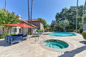 Sacramento apartment for rent - A pool area with a hot tub and a patio with chairs and a table.