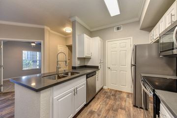 Vacaville apartment for rent - A kitchen with white cabinets and a black countertop.