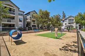 San Jose apartment for rent - A playground with a blue slide and a green area in front of apartment buildings.