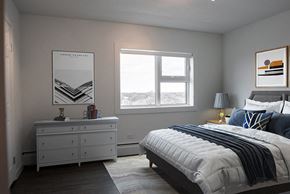 Winnipeg apartment for rent - A bedroom with a large bed and a dresser with a mirror.