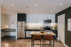 Winnipeg apartment for rent - a kitchen with white cabinets and stainless steel appliances and a wooden table