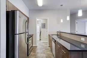 Winnipeg apartment for rent - A kitchen with a black refrigerator and a black counter top.