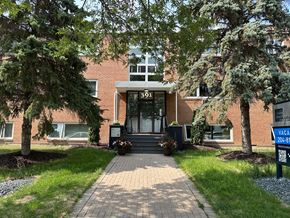 Winnipeg apartment for rent - a brick building with a black door and a tree in front of it