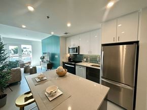 Winnipeg apartment for rent - A modern kitchen with a stainless steel refrigerator and a dining table set with plates and bowls.