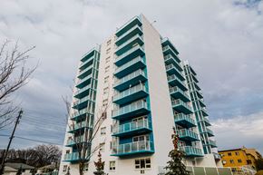Winnipeg apartment for rent - a tall building with green balconies and a cloudy sky
