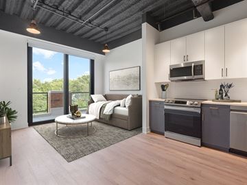 Chicago apartment for rent - A modern kitchen with a stainless steel oven and microwave, a grey countertop, and a living area with a sofa and coffee table.