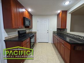 Medford apartment for rent - a kitchen with brown cabinets and black counter tops and a white door