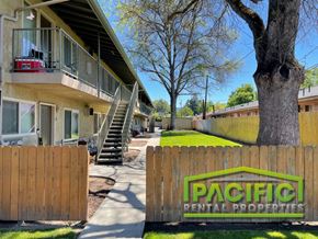 Medford apartment for rent - a fence with a pacific rental properties sign in front of a building