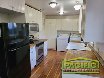 Ashland apartment for rent - a kitchen with white cabinets and appliances and a black refrigerator