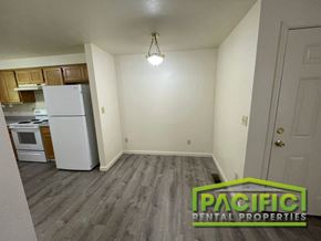 Medford apartment for rent - an empty living room with a kitchen with a refrigerator and