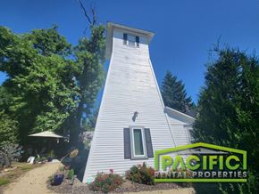 Medford apartment for rent - A white house with a green logo for Pacific Rental Properties in front of it.