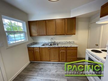 Medford apartment for rent - A kitchen with wooden cabinets and a white stove top oven.