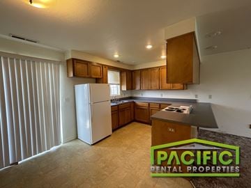 Medford apartment for rent - A kitchen with a refrigerator, cabinets, and a countertop is shown in an empty apartment.