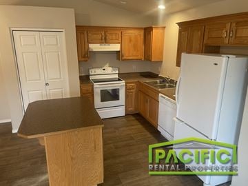 Grants Pass apartment for rent - A kitchen with a white refrigerator, stove, and oven.