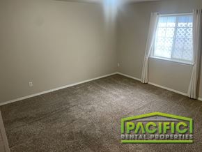 Grants Pass apartment for rent - A room with a carpeted floor and a window with white curtains.